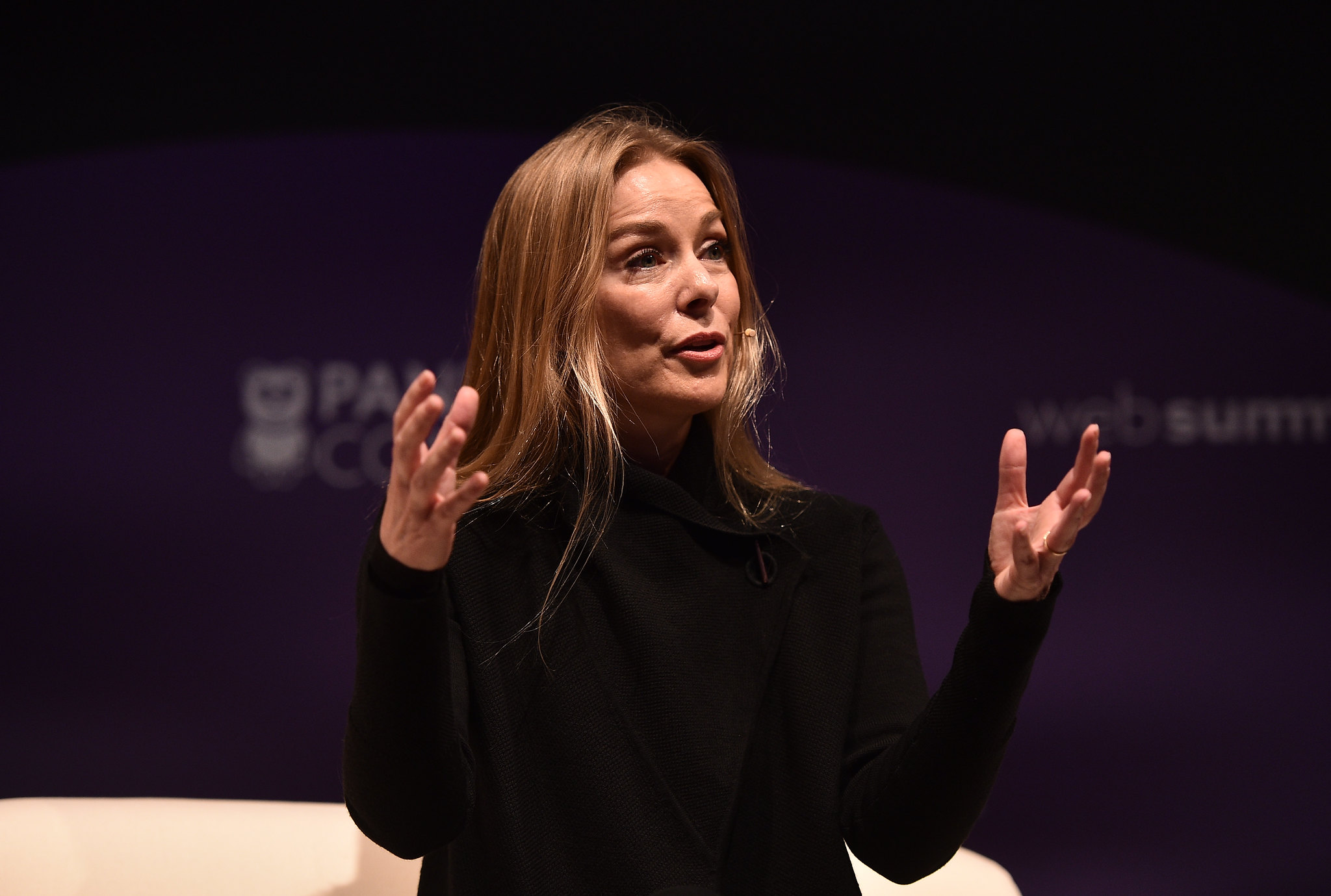 Photograph of a person (Sairah Ashman, global CEO of Wolff Olins) speaking on stage at Web Summit. They are gesturing with their hands and appear to be speaking to an audience.