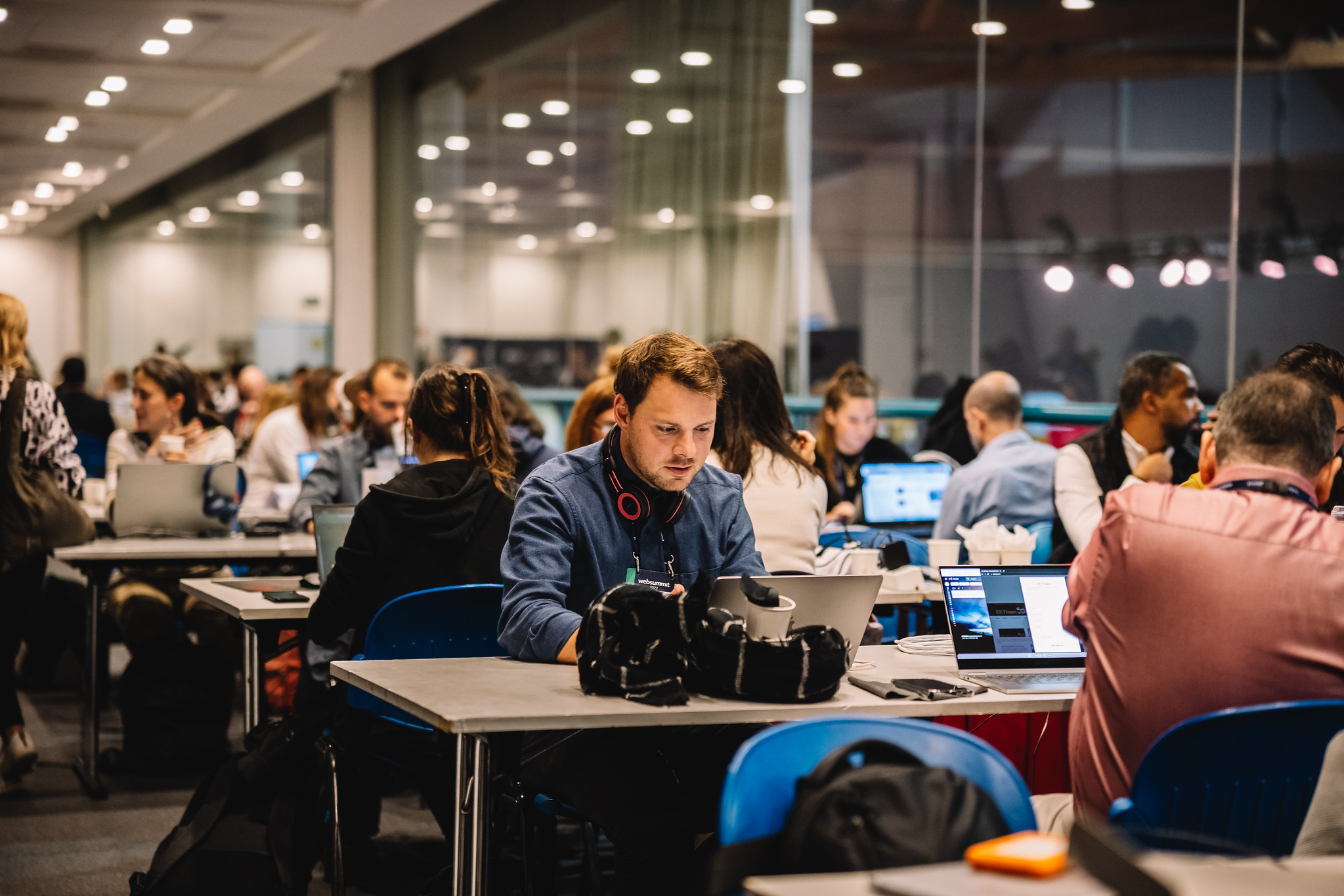 Journalists work sitting at tables in the pressroom during the web summit 2022