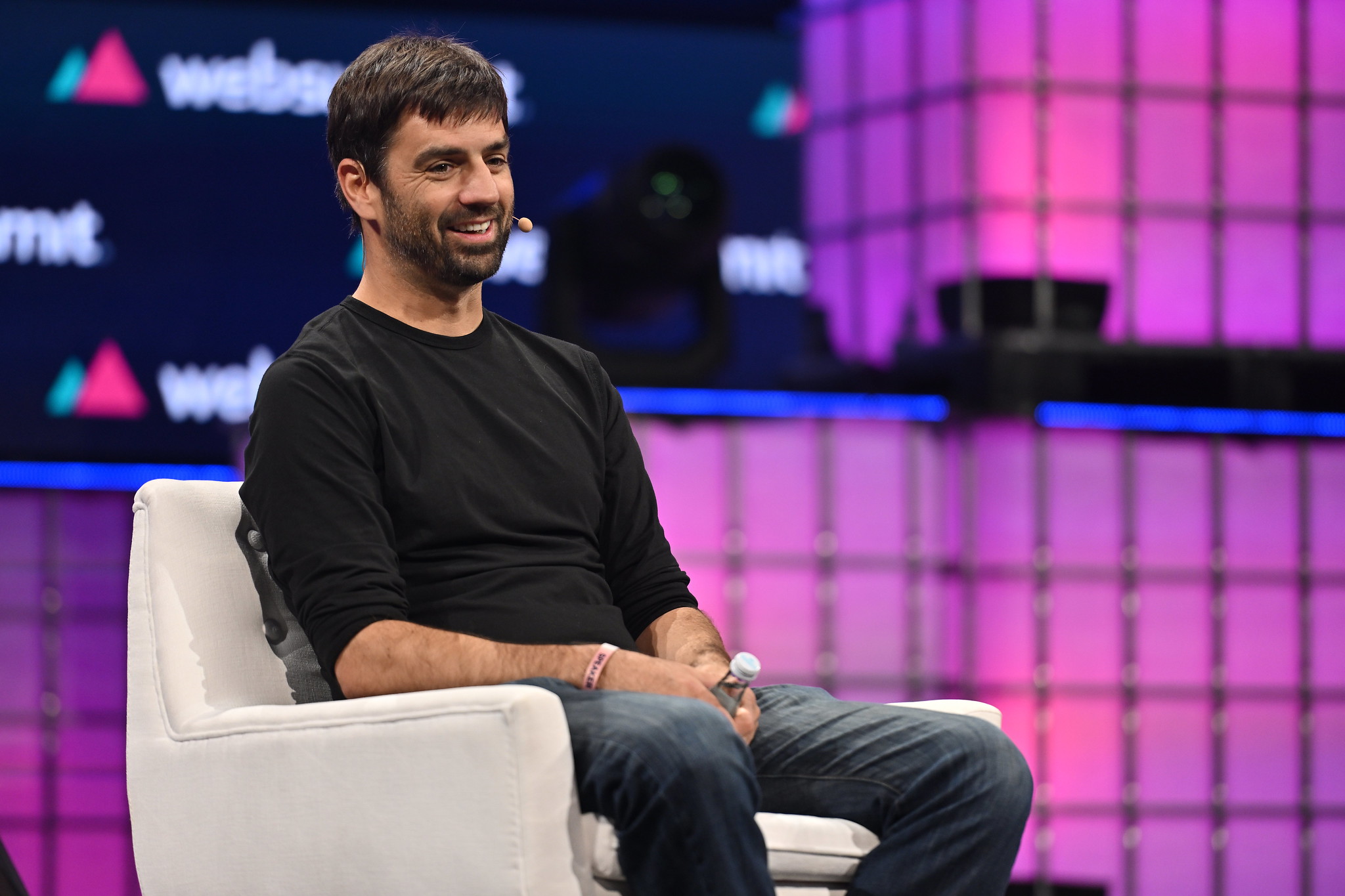 A photograph of Zach Coelius, founder of Coelius Capital, sitting on a chair on Centre Stage at Web Summit. Zach appears relaxed, and appears to be smiling. Zach is facing away from the camera and towards an audience that is not visible in the photo.