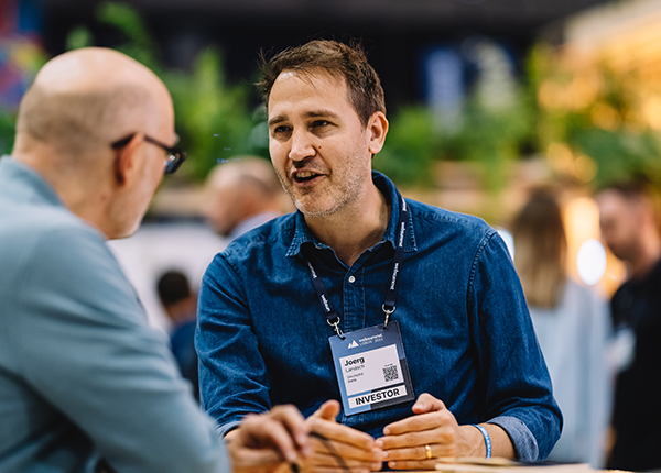 A photograph of an investor at Web Summit. The investor appears to be speaking to another person.