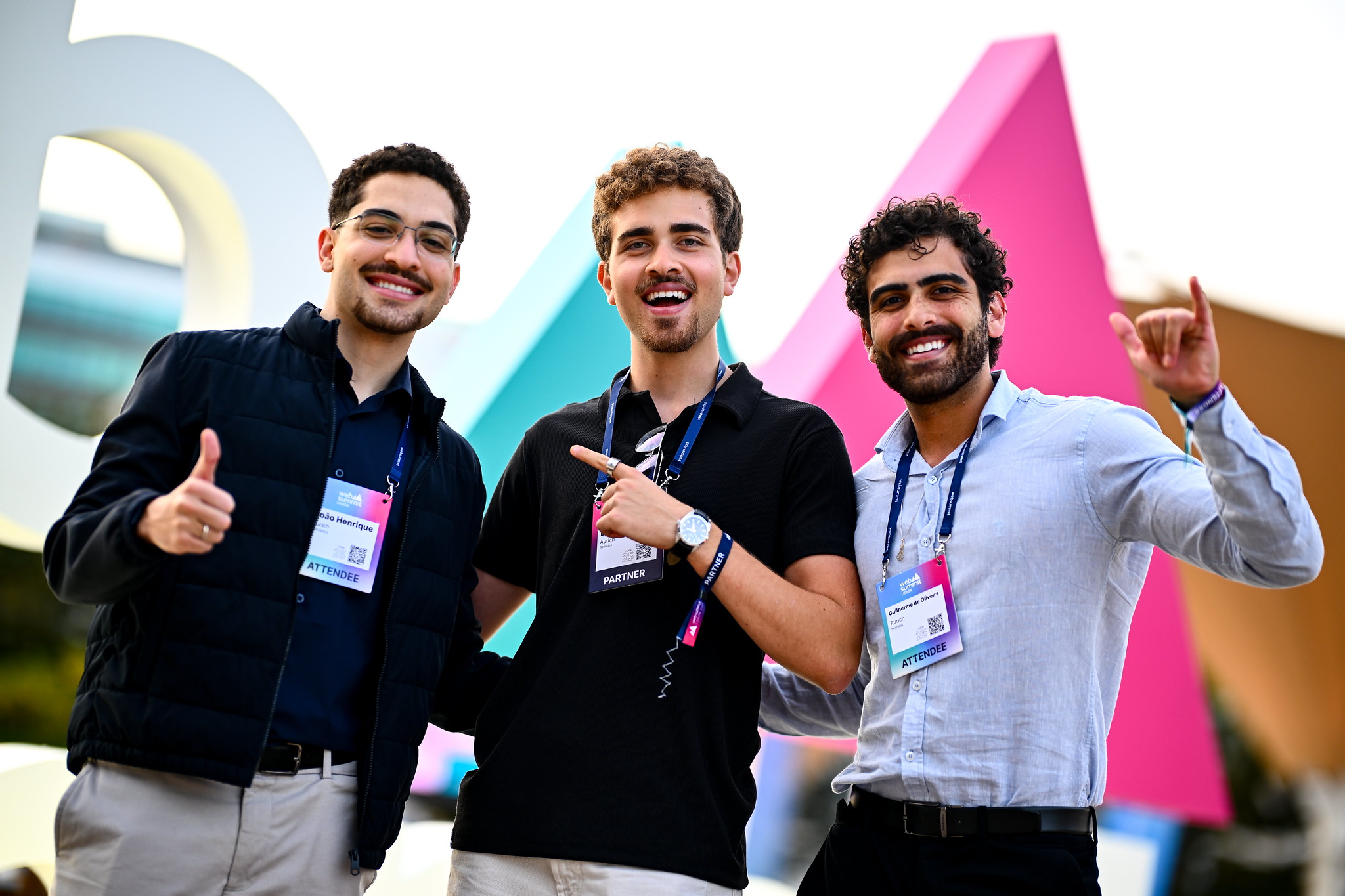 Three attendees taking a photo in front of Web Summit branding during opening night