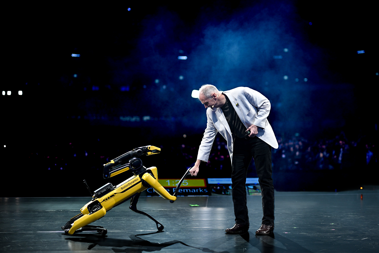 A human and a robot shaking hands on stage